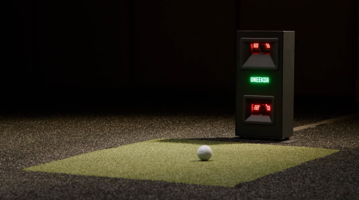 Impact Sports UNEEKOR EYE MINI Lite golf launch monitor displaying launch data and digital readouts on a screen.